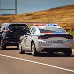 A police car drives on the highway, with another vehicle following closely behind it